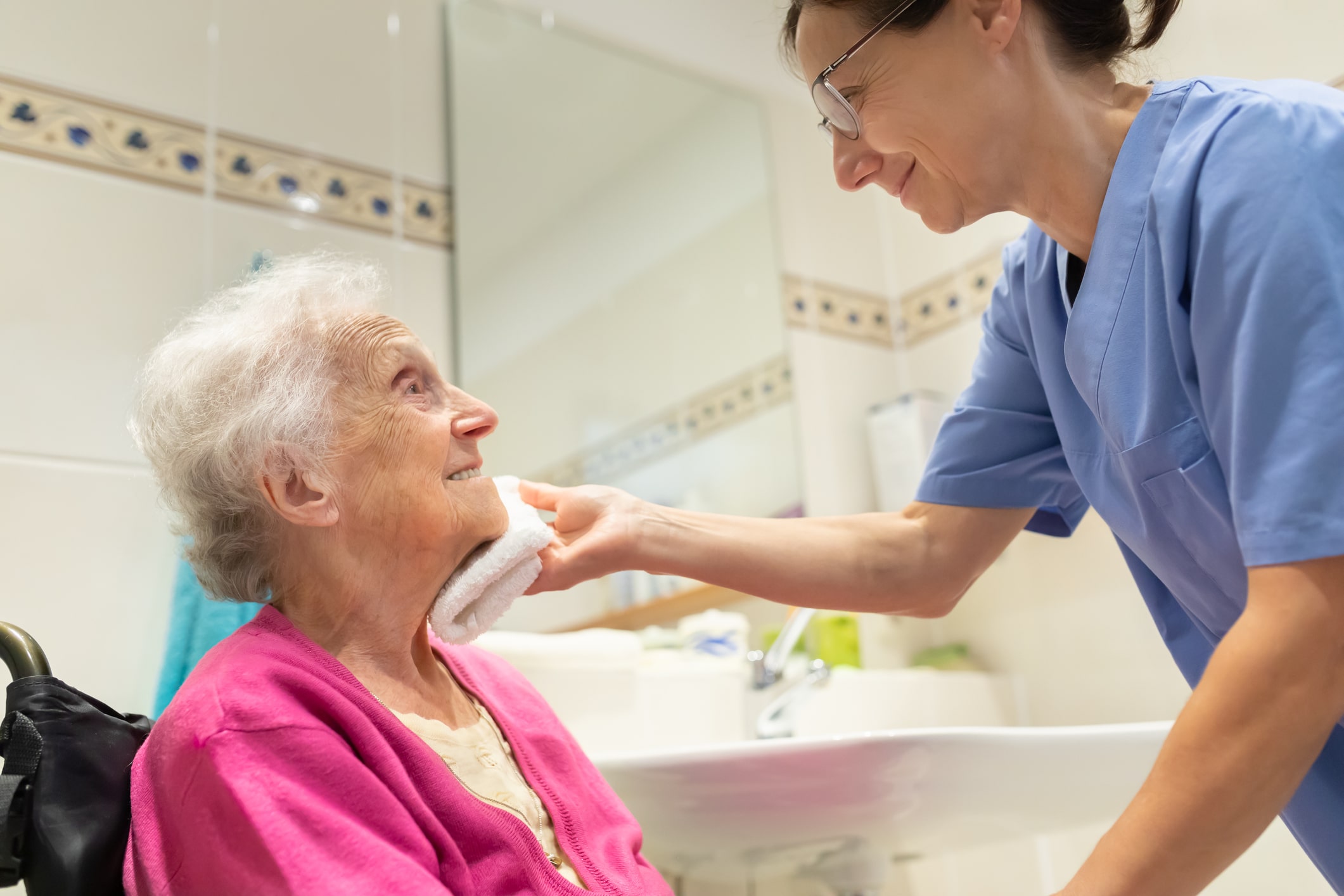 Nurse helping a patient clean face with a white towel