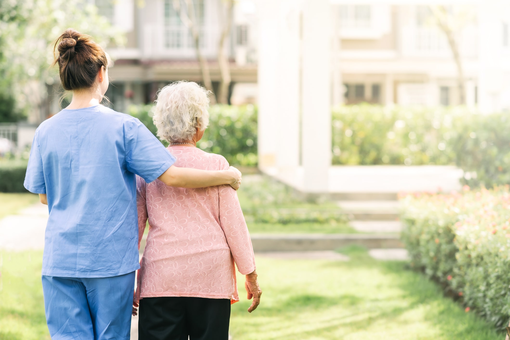 Nurse holding the right shoulder of a patient to help her walk